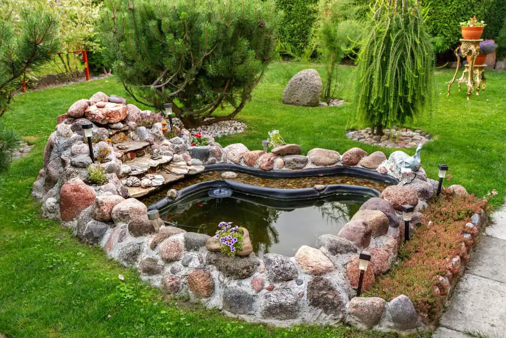 a preformed pond shell pond, in a garden. 