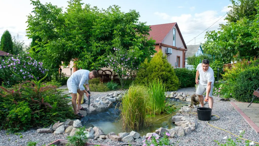 Father son duo cleaning pond with tools